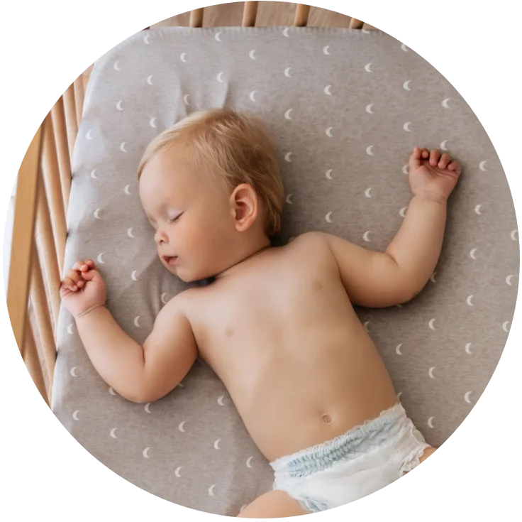 baby asleep on its back in a crib